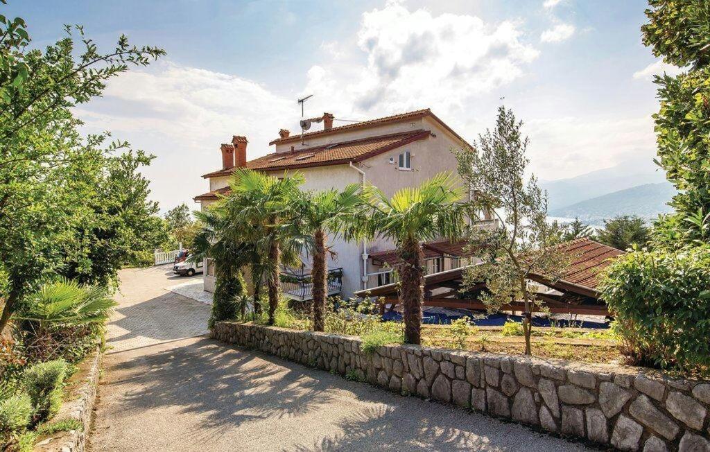 a house with a stone wall and palm trees at Apartments with a parking space Kastav, Opatija - 15287 in Kastav