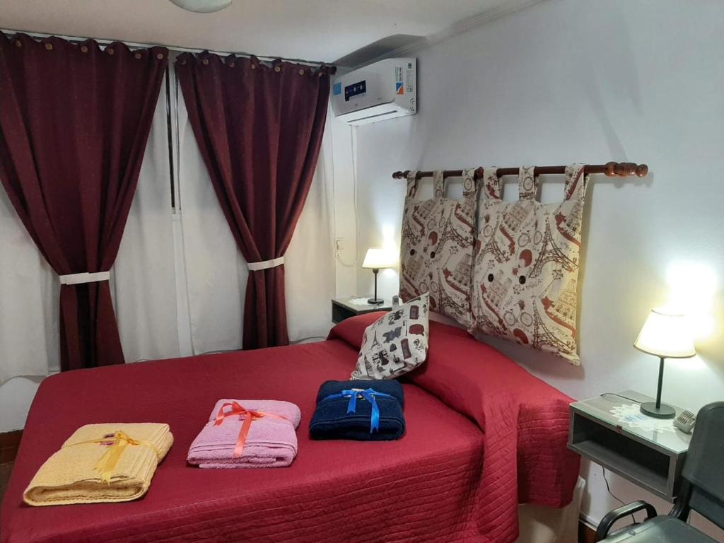 M & Mendoza في ميندوزا: غرفة نوم بسرير احمر وعليها شنطتين
