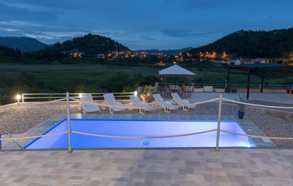 a swimming pool with chairs and a volleyball court at Family friendly apartments with a swimming pool Bacina, Neretva Delta - Usce Neretve - 15309 in Ploče