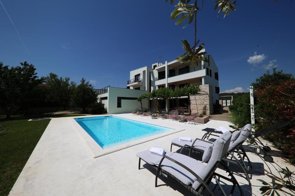 Villa mit einem Pool mit Stühlen und einem Gebäude in der Unterkunft Holiday house with a swimming pool Zadar - Diklo, Zadar - 15336 in Zadar