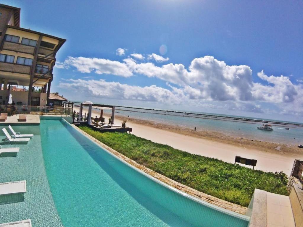 un complexe avec une piscine à côté de la plage dans l'établissement Apartamento em Barra Bali, Resort de Luxo - Destino BSM 329, à Barra de São Miguel