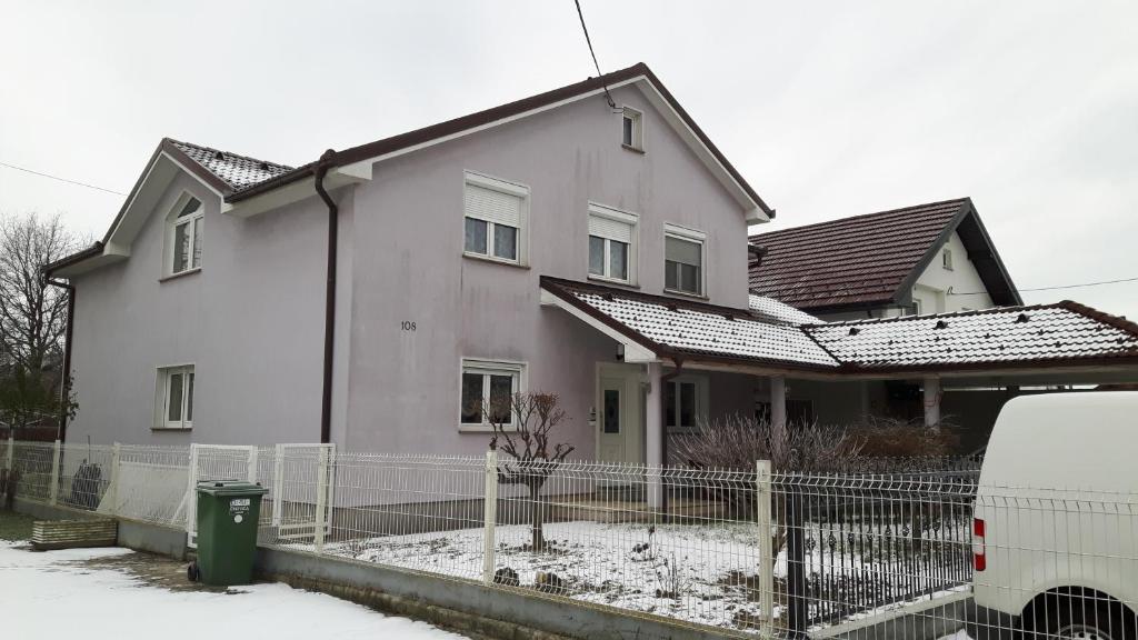 ein weißes Haus mit einem Zaun davor in der Unterkunft Apartments with a parking space Zagreb - 15343 in Brezovica