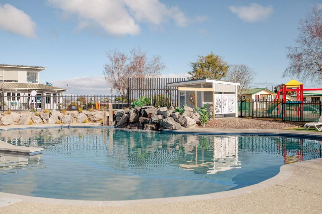 een zwembad in een tuin met een speeltuin bij Taupo TOP 10 Holiday Park in Taupo