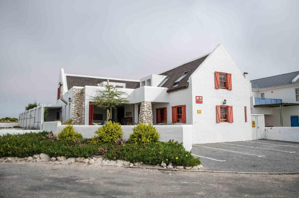 a white building with red windows and a parking lot at ah! Guest House in Paternoster