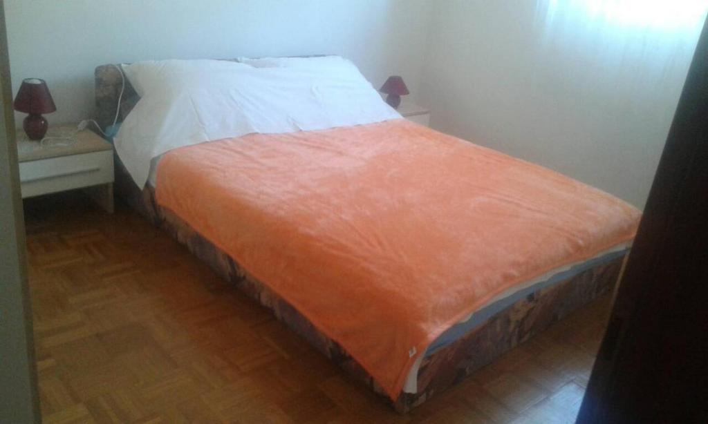 a bed with an orange blanket on it in a room at Apartments by the sea Cres - 15426 in Cres
