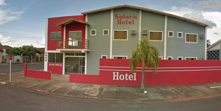 a hotel building with a palm tree in front of it at Hotel Solaris in Três Lagoas