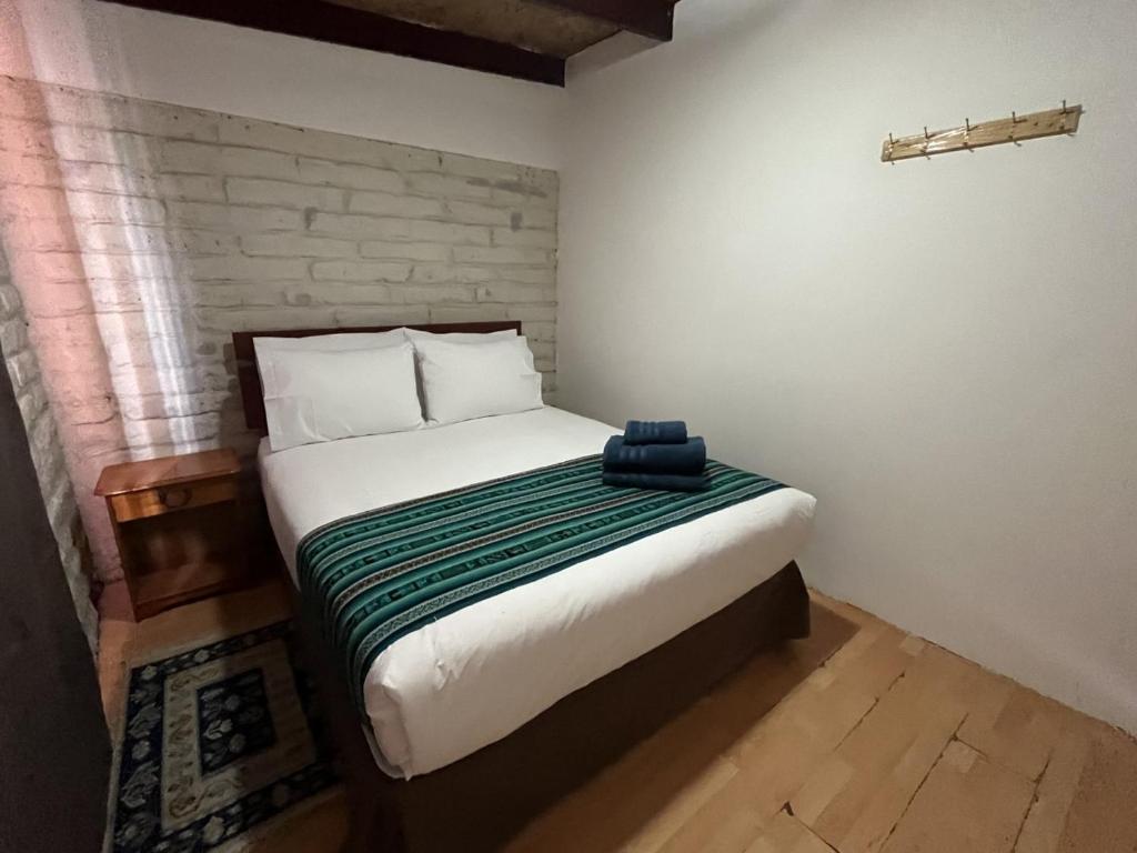 een slaapkamer met een bed met een groene en witte deken bij Ckoinatur Hostel in San Pedro de Atacama