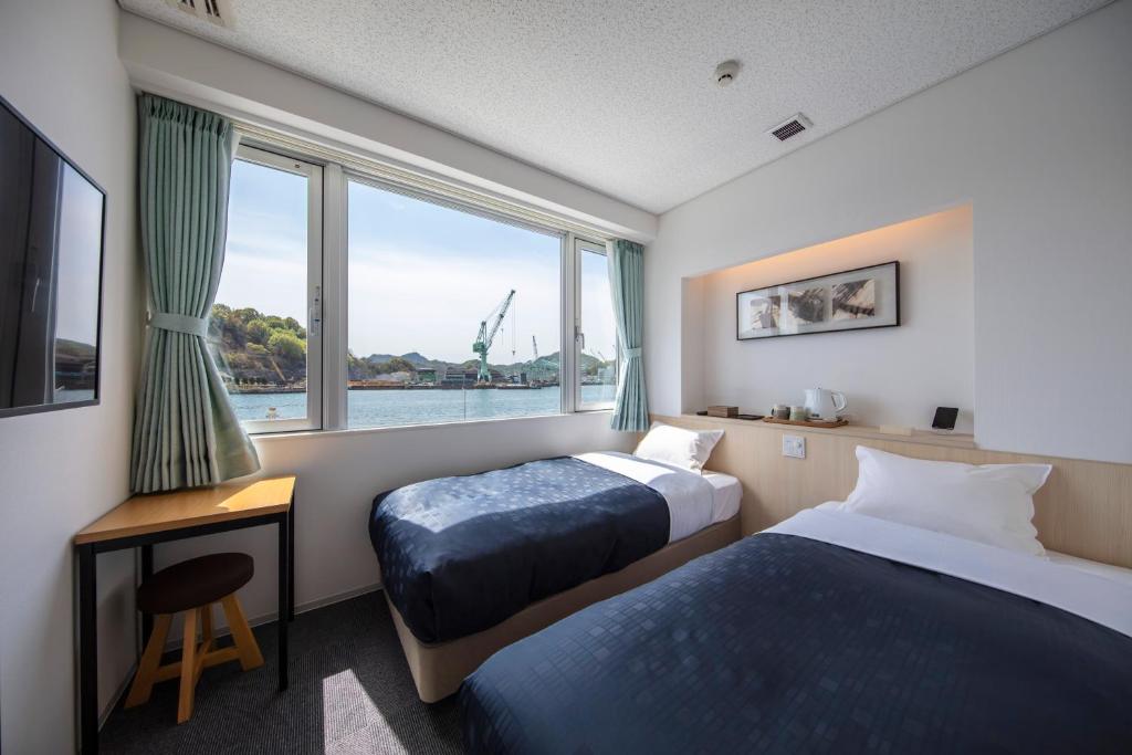 a hotel room with two beds and a window at urashima INN - GANGI - in Onomichi