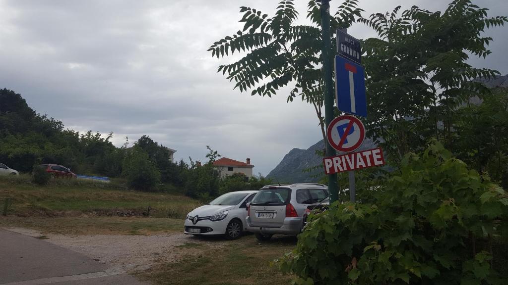 a couple of cars parked next to a street sign at Apartments by the sea Gradac, Makarska - 15642 in Gradac