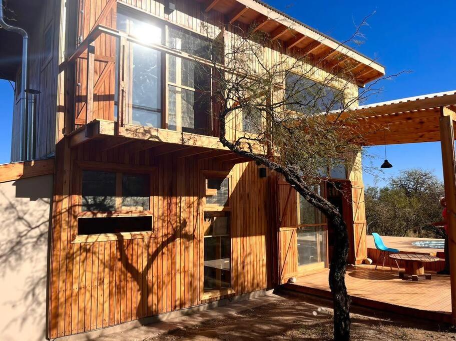 a wooden house with a tree in front of it at Mandala Tiny House, Traslasierra. in Yacanto