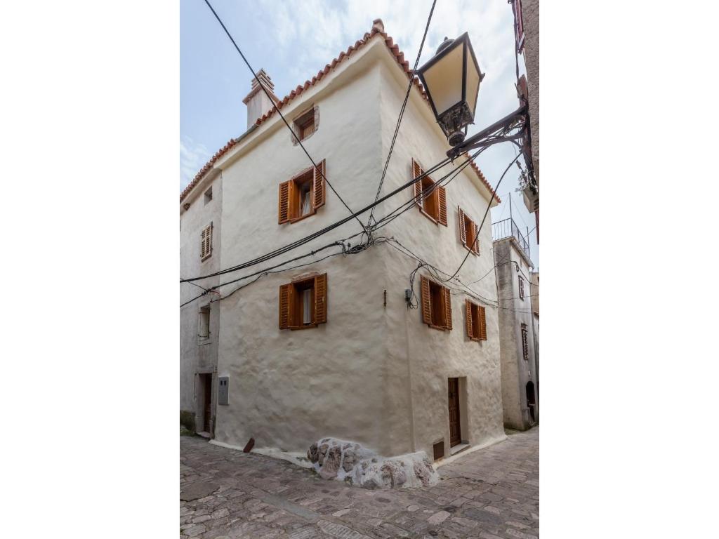 an old white building with wooden windows on a street at Apartments with WiFi Vrbnik, Krk - 15721 in Vrbnik