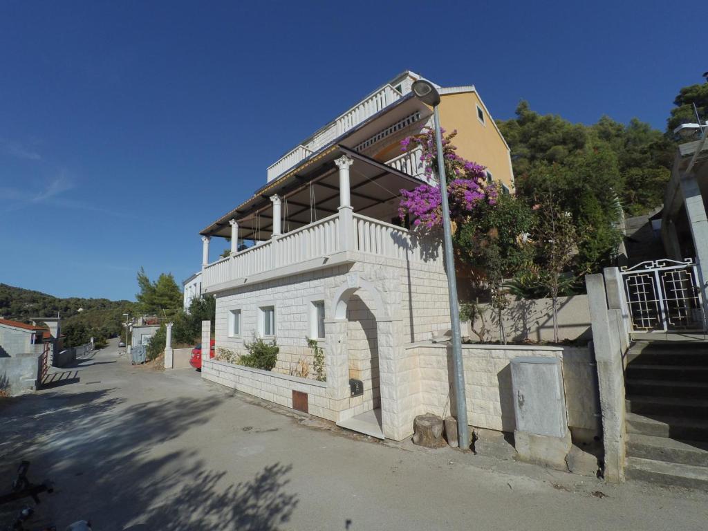 ein weißes Gebäude mit Balkon auf einer Straße in der Unterkunft Apartments by the sea Brna, Korcula - 15730 in Smokvica