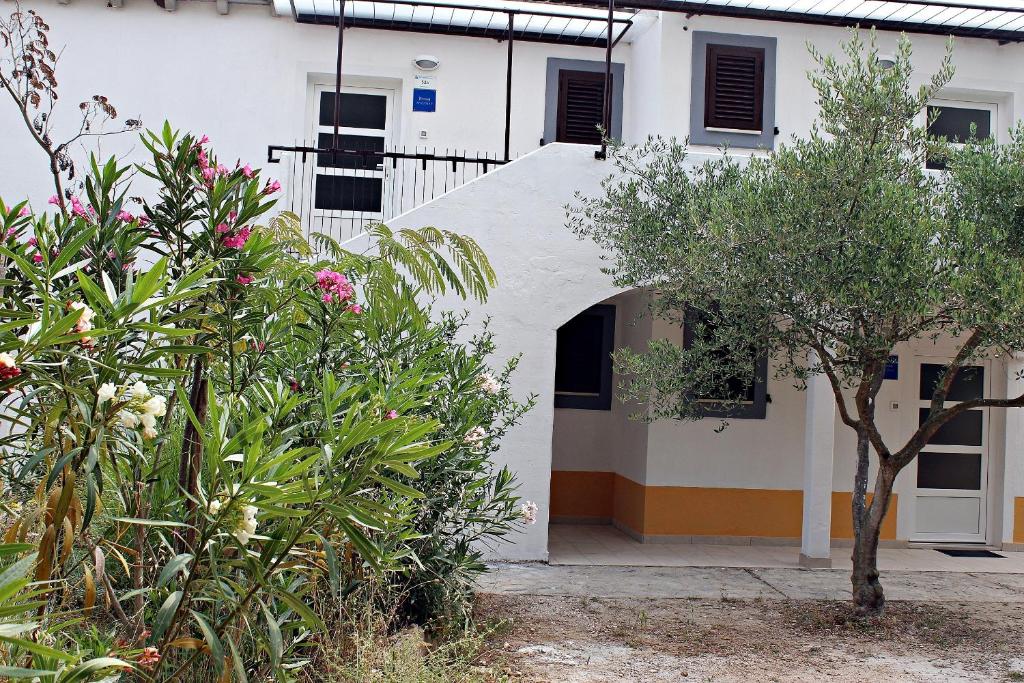 a white building with trees and flowers in front of it at Apartments with a parking space Nerezine, Losinj - 15768 in Nerezine