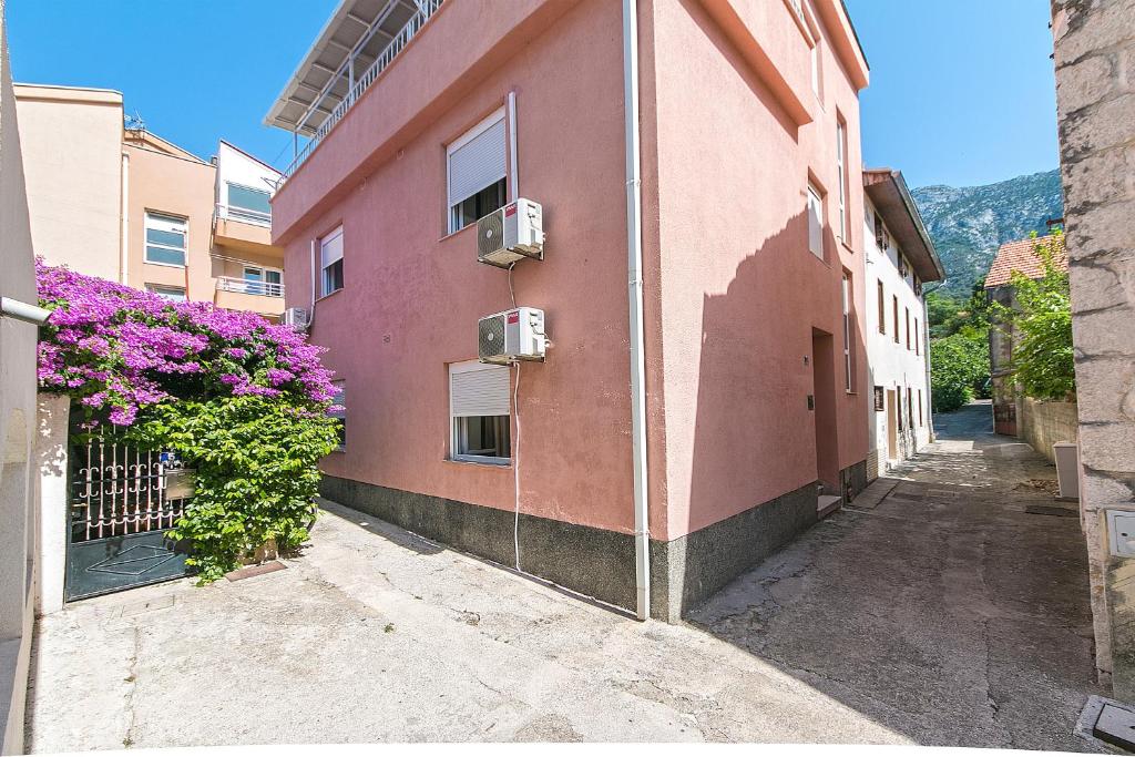 un edificio rosa con dei fiori sul lato di Triple Room Gradac 16006c a Gradac (Grado)