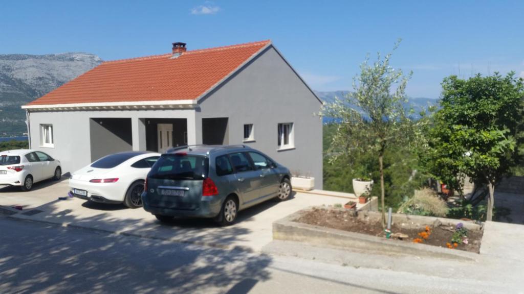 een huis met twee auto's geparkeerd op een parkeerplaats bij Apartments with a parking space Zrnovo, Korcula - 16045 in Korčula