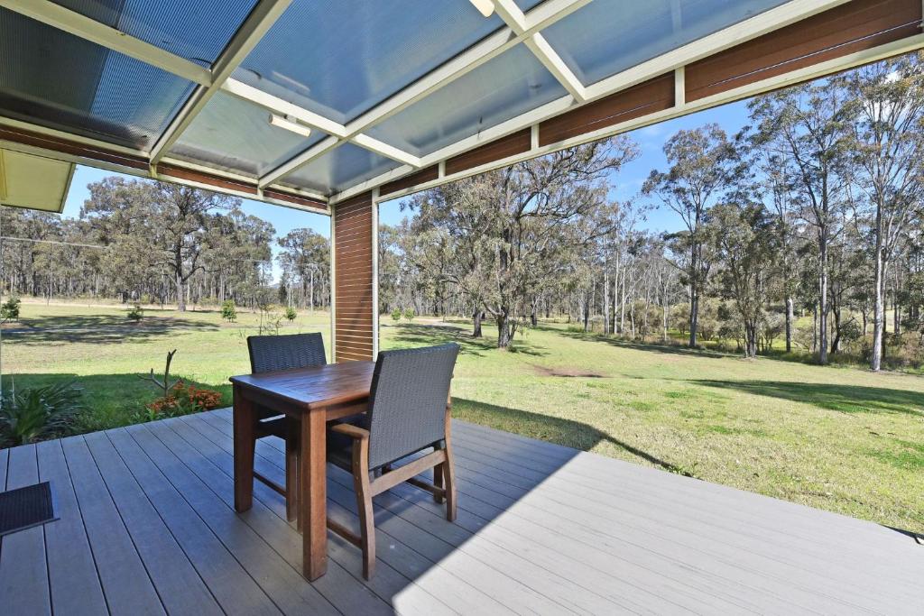a porch with a wooden table and two chairs at Ironbark Hill Villa 1 Tyrian in Pokolbin