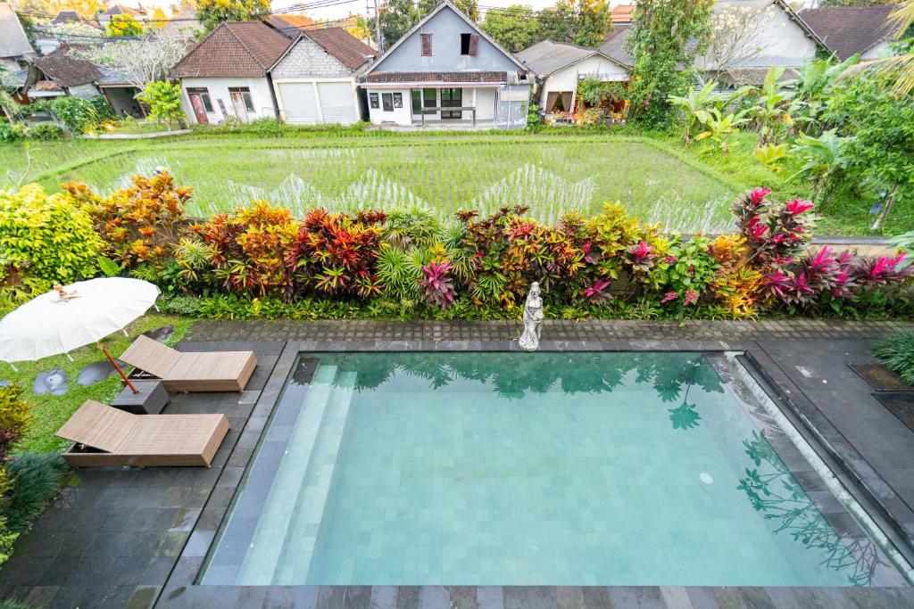 a swimming pool with two chairs and an umbrella at The Dayuh Ubud in Ubud