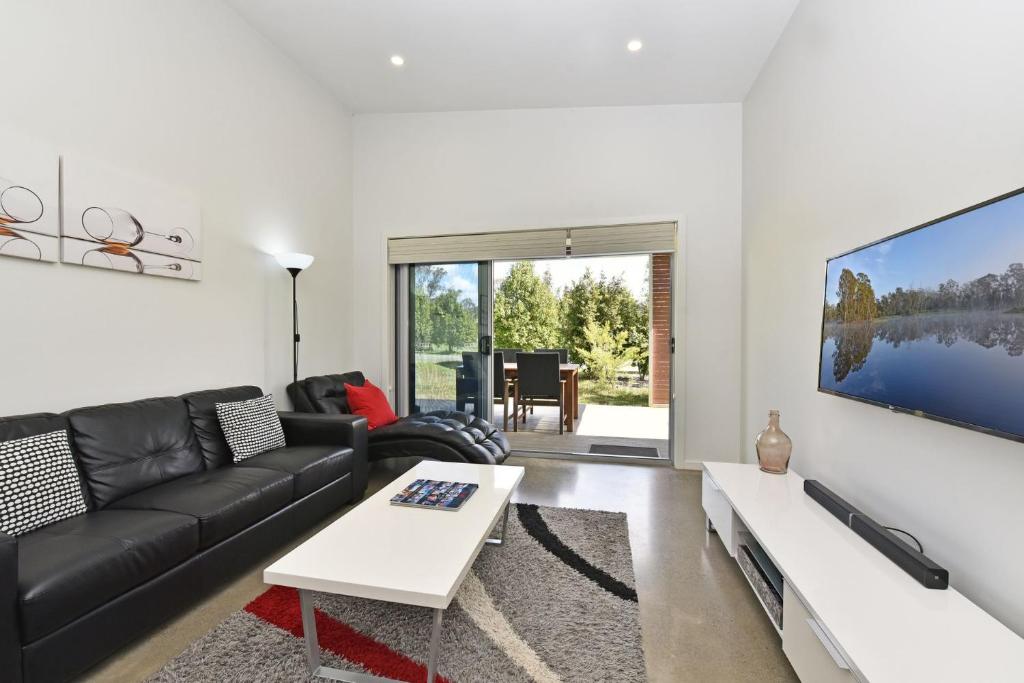 a living room with a black couch and a tv at Ironbark Hill Villa 2 Aneis in Pokolbin