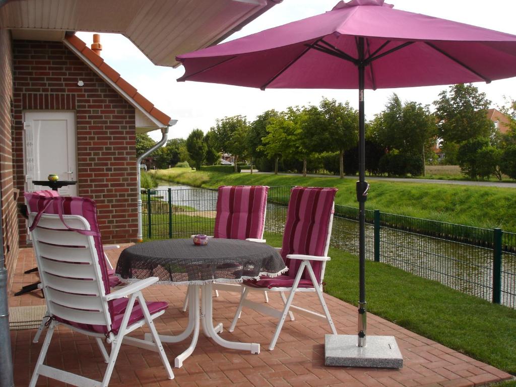 - 2 chaises et une table avec un parasol sur la terrasse dans l'établissement Grachtenstube, à Greetsiel