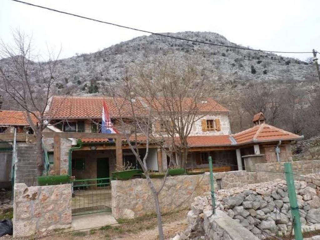 a house with a stone wall in front of a mountain at Holiday house with a parking space Starigrad, Paklenica - 16126 in Starigrad
