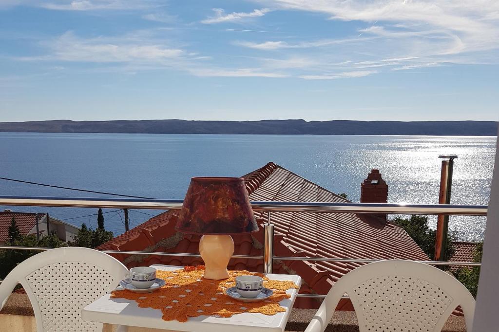 a table with a lamp on a balcony with a view of the water at Studio Baric Draga 16148b in Barić Draga