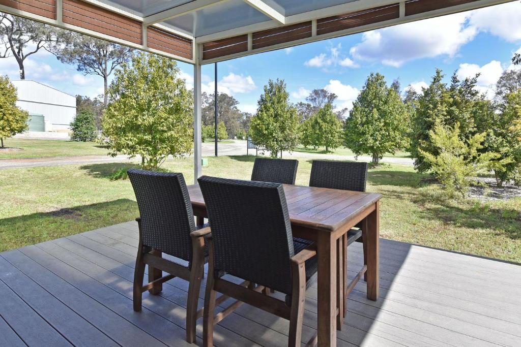 a wooden table and chairs on a deck with a view at Ironbark Hill Villa 5 Vermentino in Pokolbin