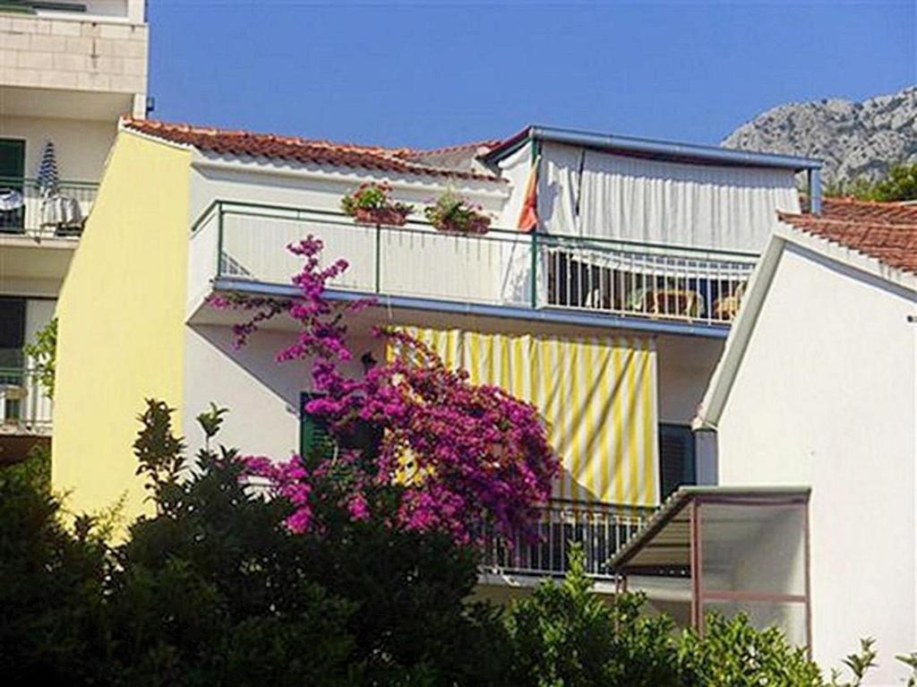 un edificio con flores púrpuras en un balcón en Apartments by the sea Podgora, Makarska - 16159 en Podgora