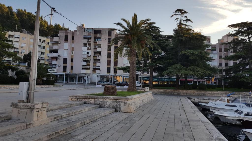 a building with a palm tree in the middle of a street at Apartments by the sea Ploce, Neretva Delta - Usce Neretve - 16195 in Ploče