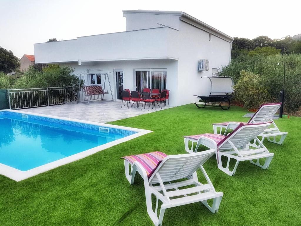 a yard with chairs and a swimming pool at Family friendly house with a swimming pool Kastel Novi, Kastela - 16199 in Kastel Novi