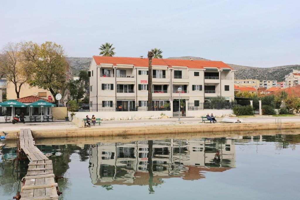 un edificio accanto a un fiume con riflessi nell'acqua di Apartments by the sea Trogir - 16211 a Trogir