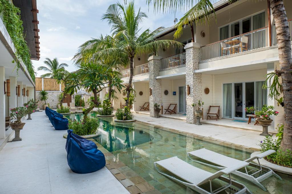 a resort pool with lounge chairs and palm trees at The Beach House Resort in Gili Trawangan