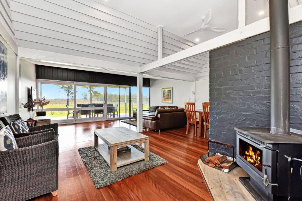 a living room with a fireplace and a couch and a table at Ironbark Hill Estate in Pokolbin