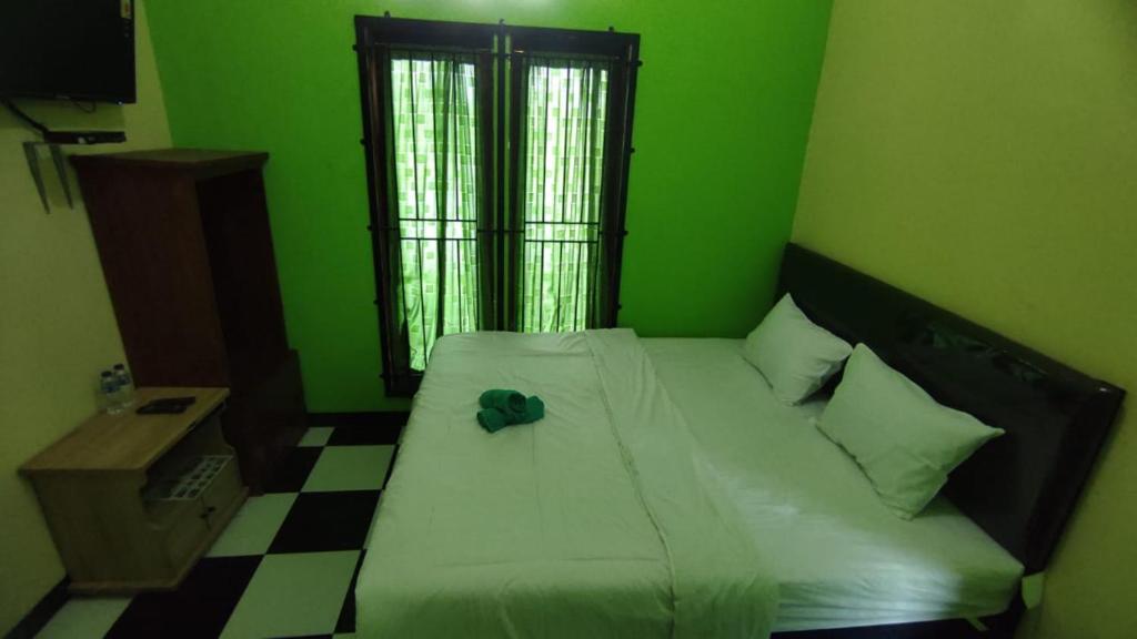 a green bedroom with a bed with a hat on it at RedDoorz near RSUD Kebumen 2 in Wanasari