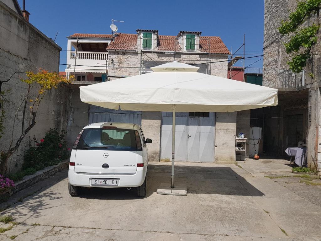 ein weißes Auto, das unter einem weißen Regenschirm geparkt ist in der Unterkunft Apartments with a parking space Vodice - 16060 in Vodice