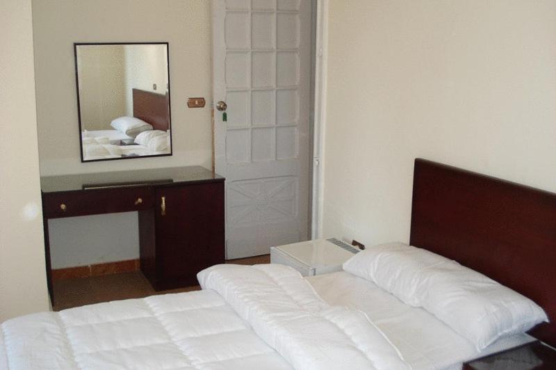 una camera con letto bianco e specchio di Transit Alexandria Hostel ad Alessandria d'Egitto