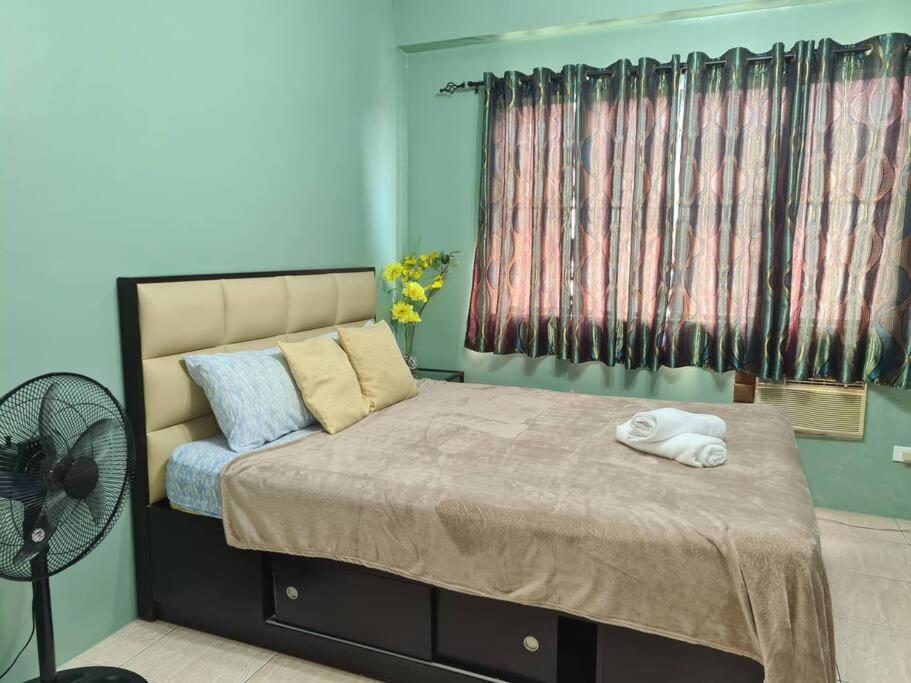 - une chambre avec un lit, un ventilateur et une fenêtre dans l'établissement Affordable staycation in Valleygolf, à Cainta