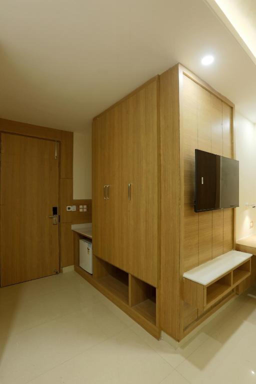 a room with wooden cabinets with a tv in it at Hotel Sakura by Maps in Gurgaon