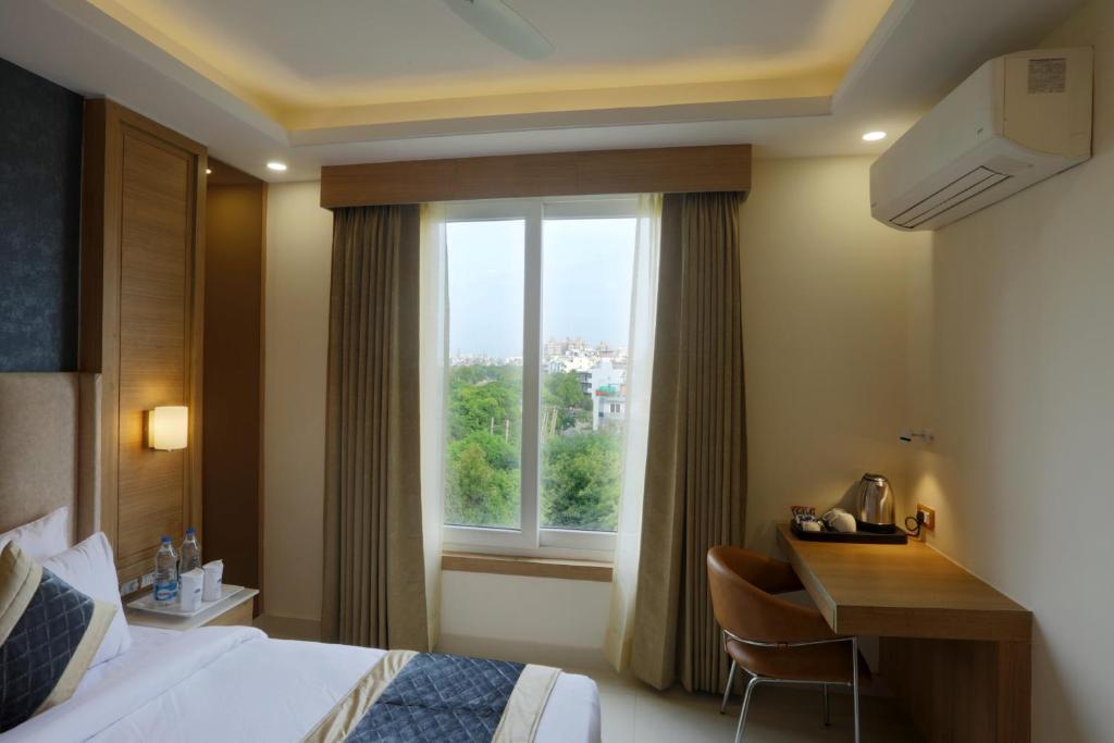 a hotel room with a bed and a desk and a window at Hotel Sakura by Maps in Gurgaon