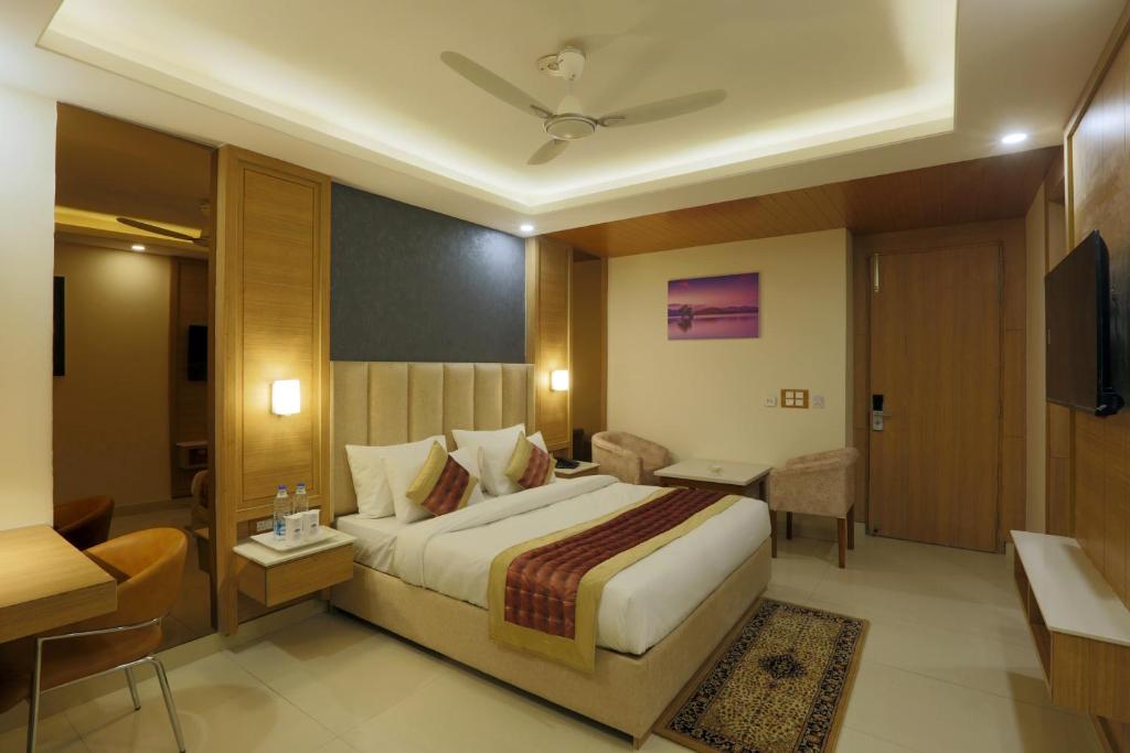 a hotel room with a large bed and a television at Hotel Sakura by Maps in Gurgaon