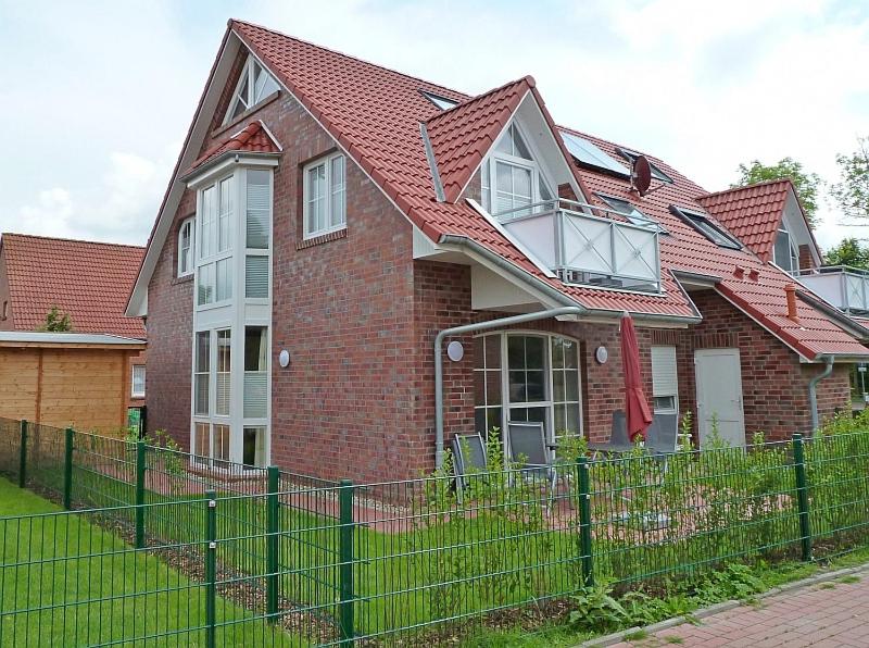 ein Backsteinhaus mit einem Zaun davor in der Unterkunft Heubude in Greetsiel