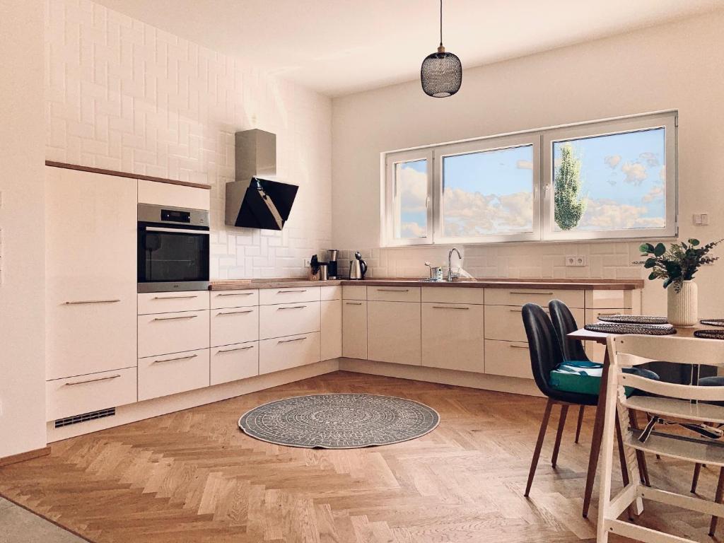 uma cozinha com armários brancos e uma mesa com cadeiras em Modernes Apartment am See mit Terrasse em Grossräschen