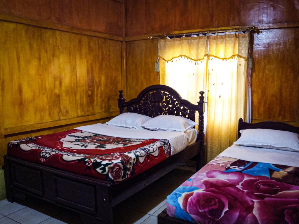 een slaapkamer met 2 bedden en een raam bij Lucas Authentic Lodge in Bajawa