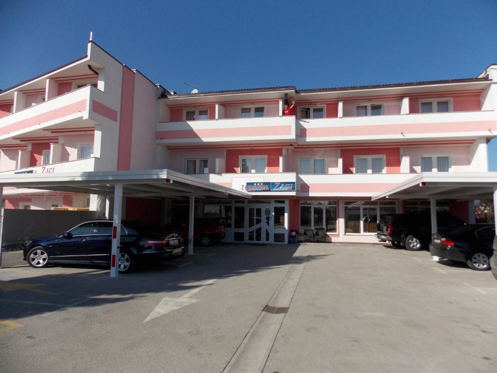 Rooms with a parking space Oroslavje, Zagorje - 15384 في Oroslavje: مبنى وردي كبير مع سيارات تقف في موقف للسيارات