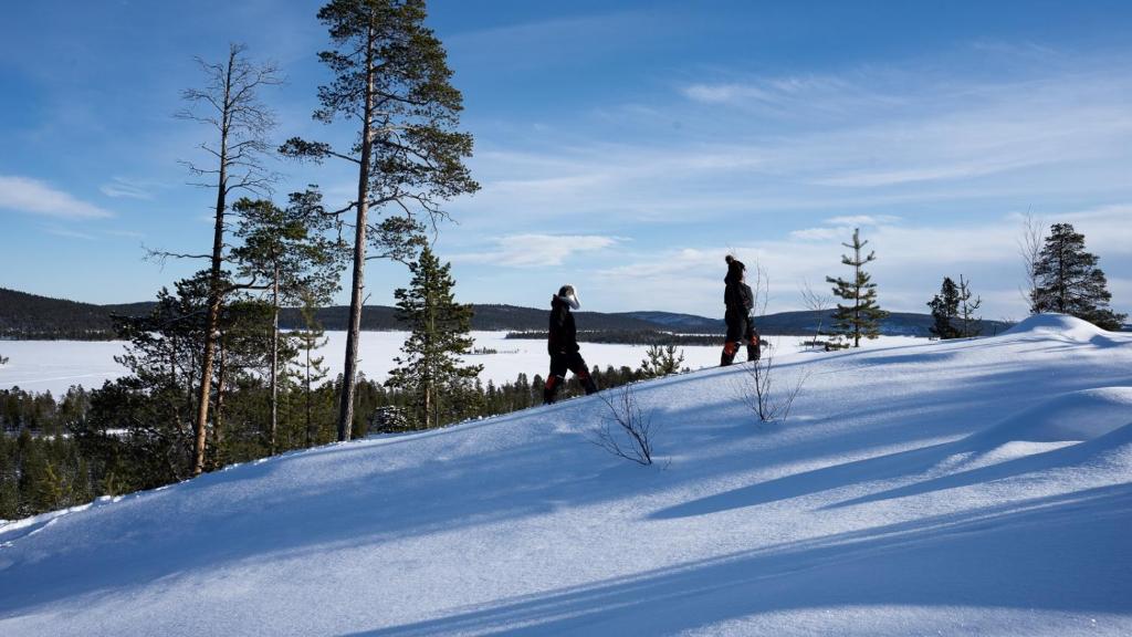 three people standing on top of a snow covered hill at Heteranta, Lake Inari / Inarijärvi in Inari