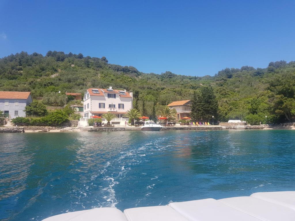 un bateau dans une masse d'eau avec des maisons dans l'établissement Rooms by the sea Rava, Dugi otok - 15880, à Rava