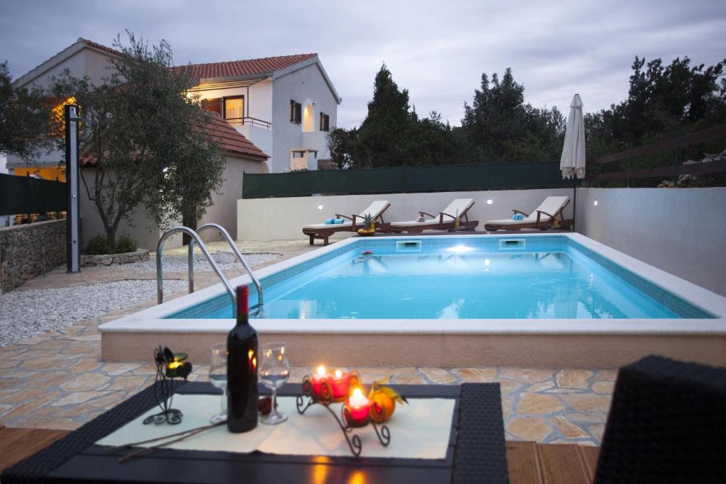 a swimming pool with a bottle of wine next to it at Apartments with a swimming pool Razanj, Rogoznica - 16182 in Rogoznica