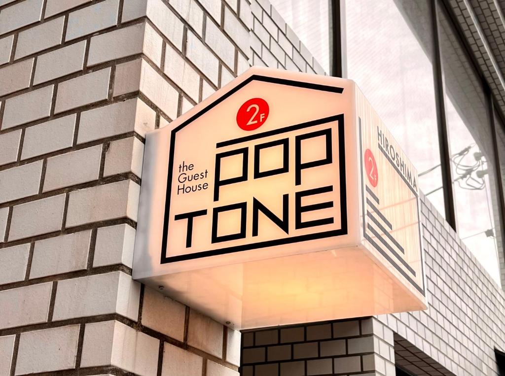 a sign on a building that reads the guest house tone at Guesthouse POPTONE in Hiroshima