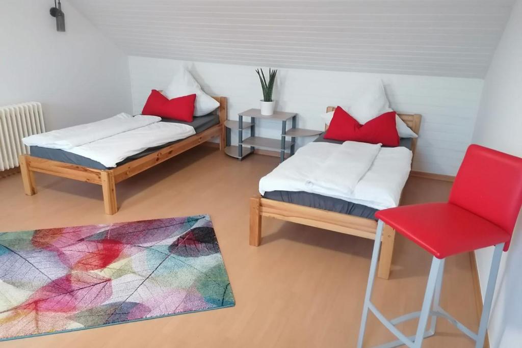 NiederdorfeldenにあるCozy Apartment near Frankfurtのベッド2台と赤い椅子が備わる客室です。