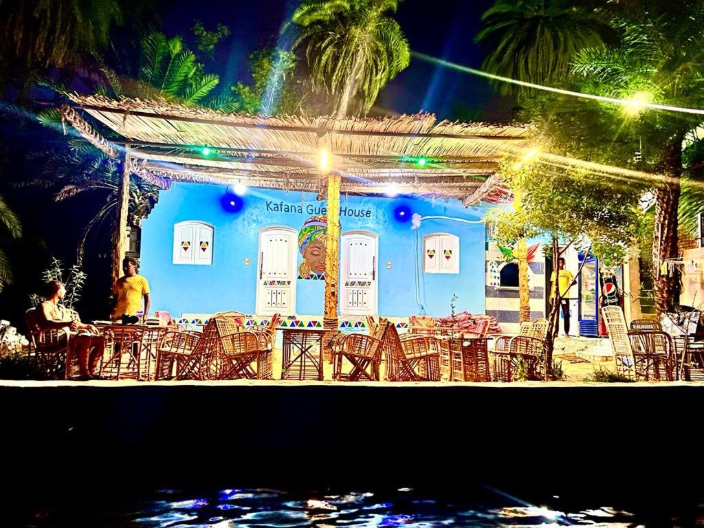 a group of tables and chairs in front of a blue building at Kafana Guest House Nile View in Aswan