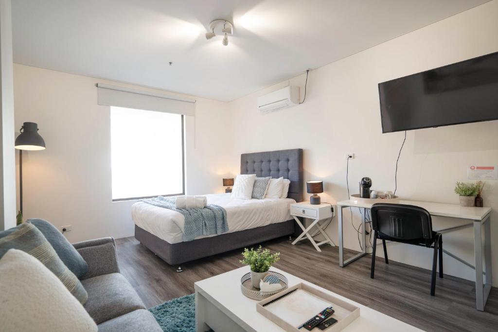 a bedroom with a bed and a desk in a room at 206 Funky Executive Studio Cbd Ac in Perth